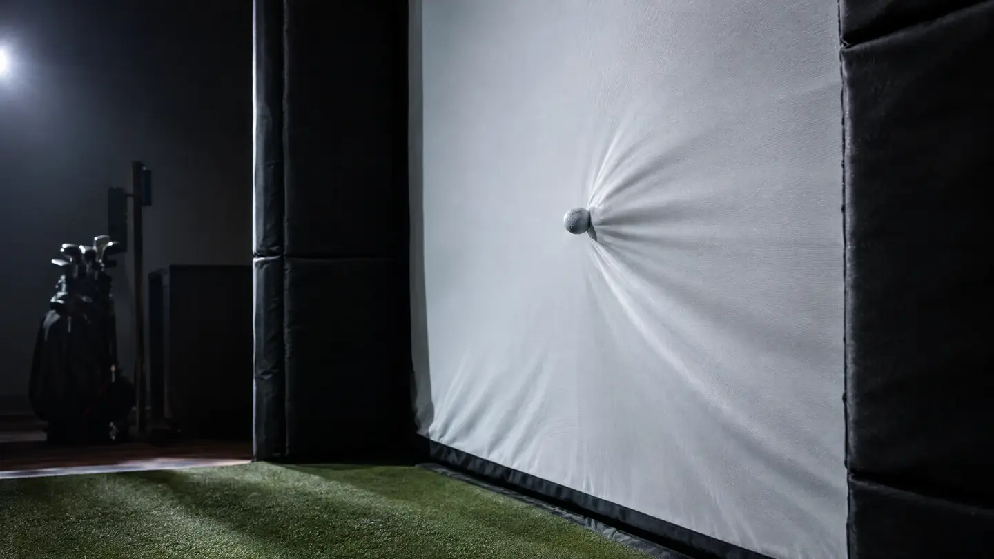 Golf simulator enclosure with an impact screen and a golf ball hitting it
